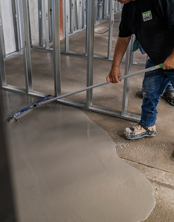 BNE worker applying concrete self-levelling underlay which will be finished with an epoxy or urethane coating